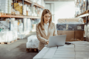 woman on warehouse using quickbooks online on her laptop